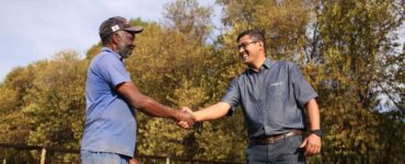 Dois homens se cumprimentando em uma fazenda